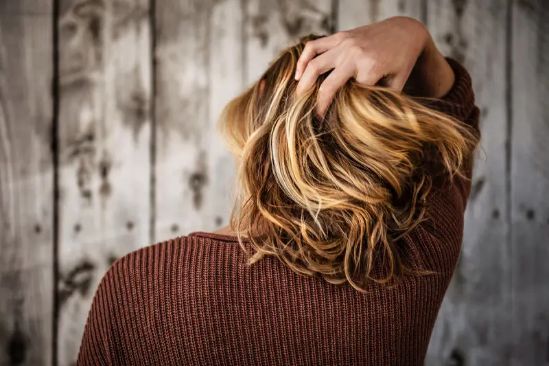 Vrouw met de hand in haar blonde haar