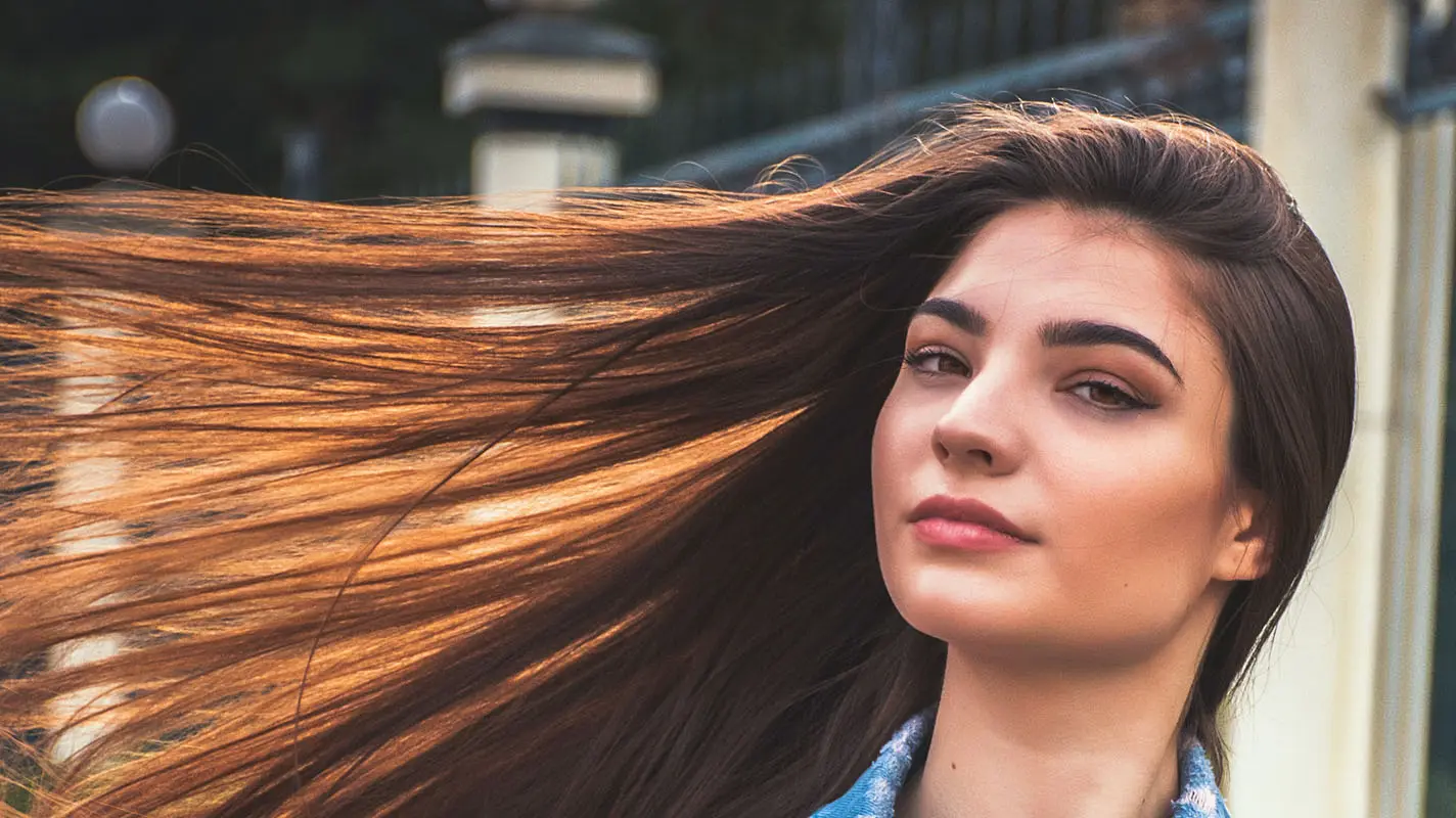 Vrouw met lang bruin haar dat in de wind waait